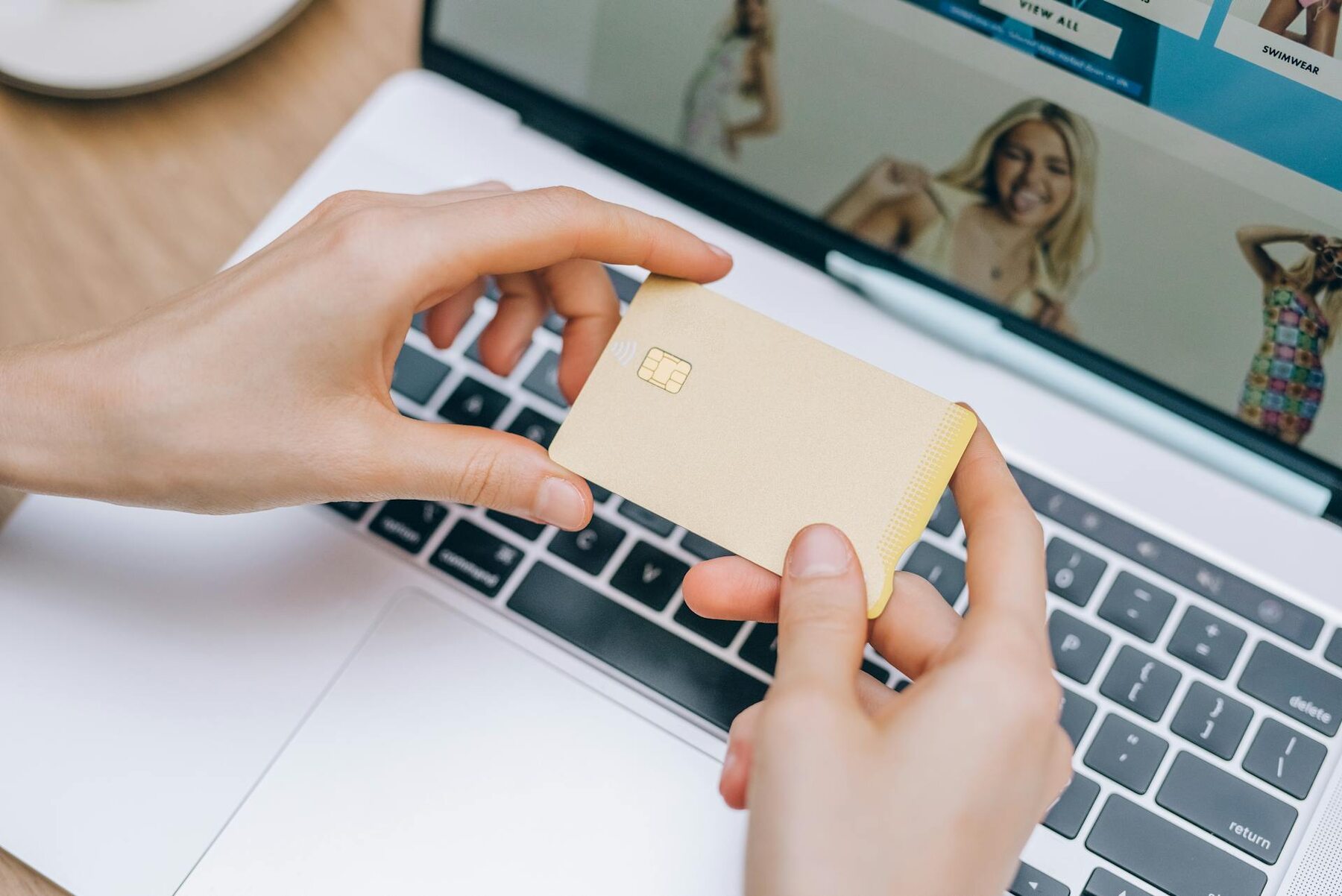 Woman holding a blank credit card while her laptop is open
