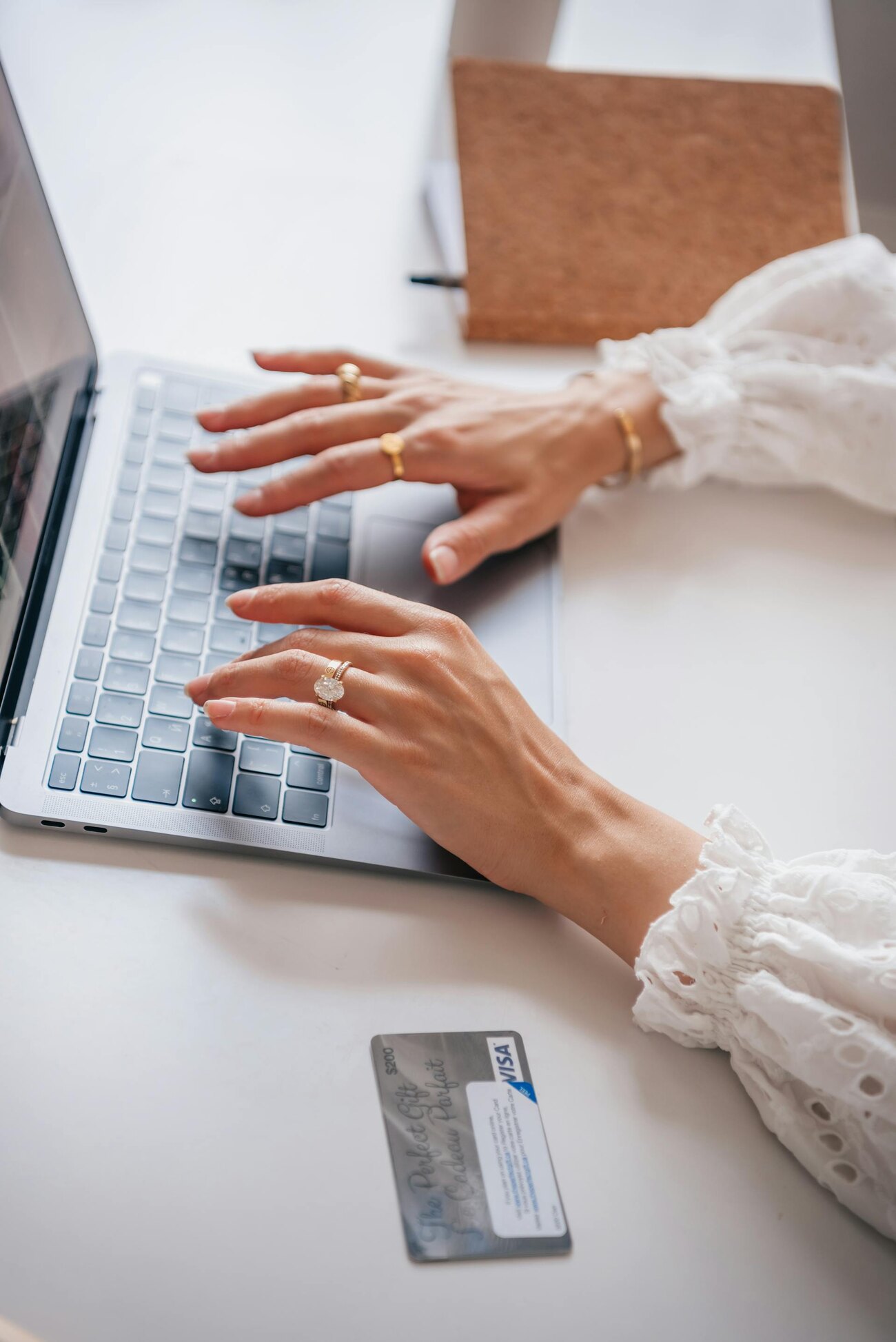 A woman sitting at a desk typing on a laptop with a credit card nearby