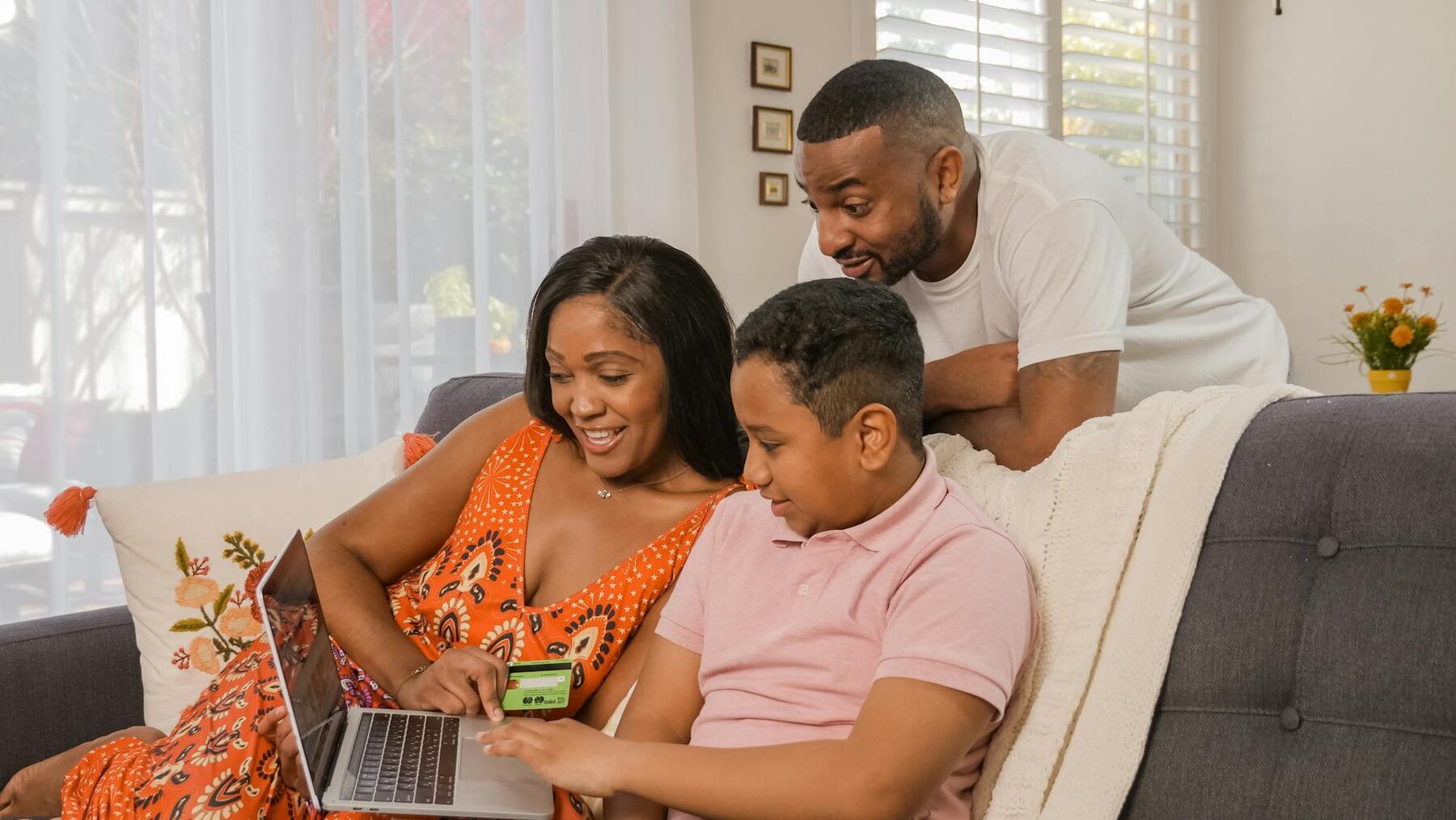 A family sitting on a couch with a laptop, enjoying quality time together at home