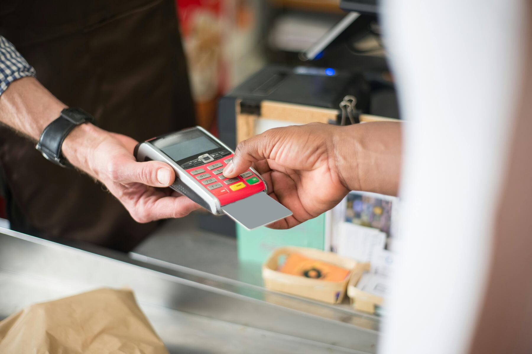 A cashier holding a terminal payment while the customer types their PIN number