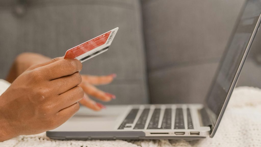 A woman holding a credit card while typing on her laptop