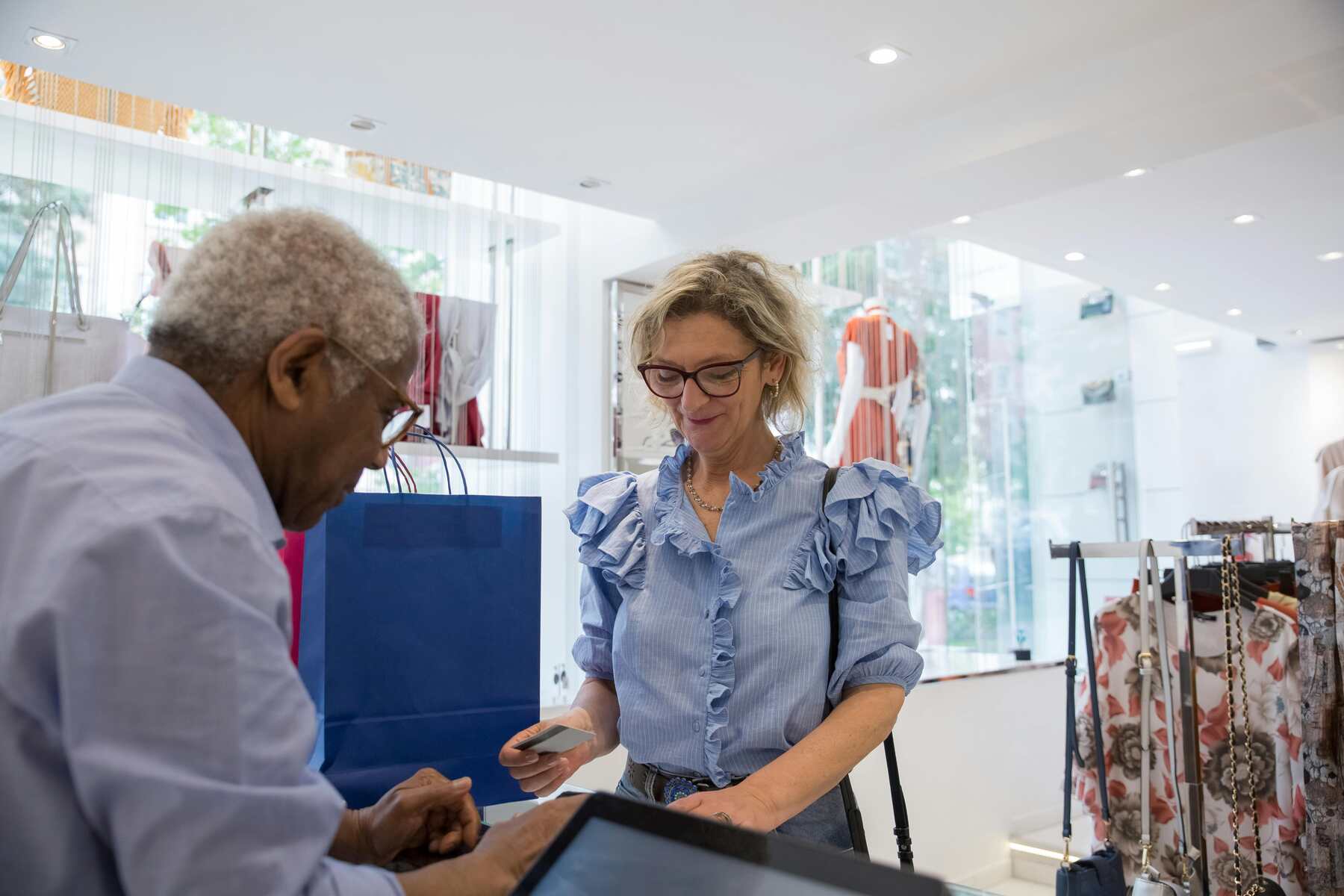 An woman holding a credit card while the cashier entertains her