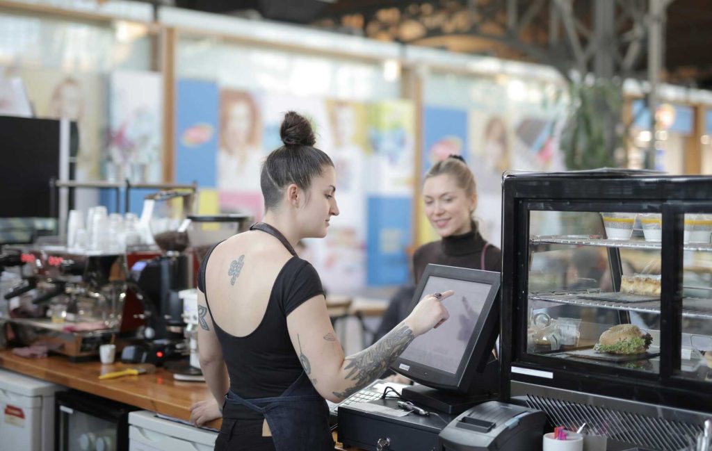 A cashier in the coffee shop processing the order of a customer