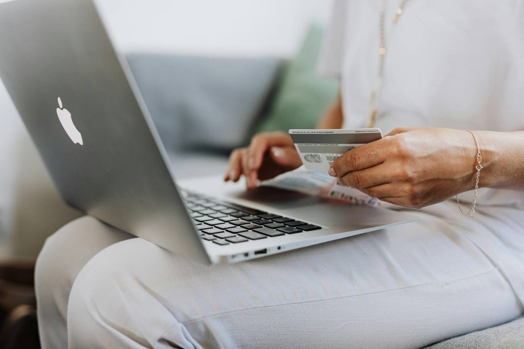 A woman holding her credit card and typing on the laptop